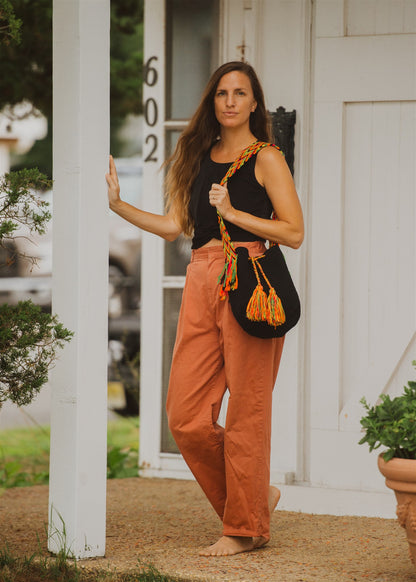 Woman standing on porch looking at camera wearing black crochet boho shoulder bag with multicolored strap